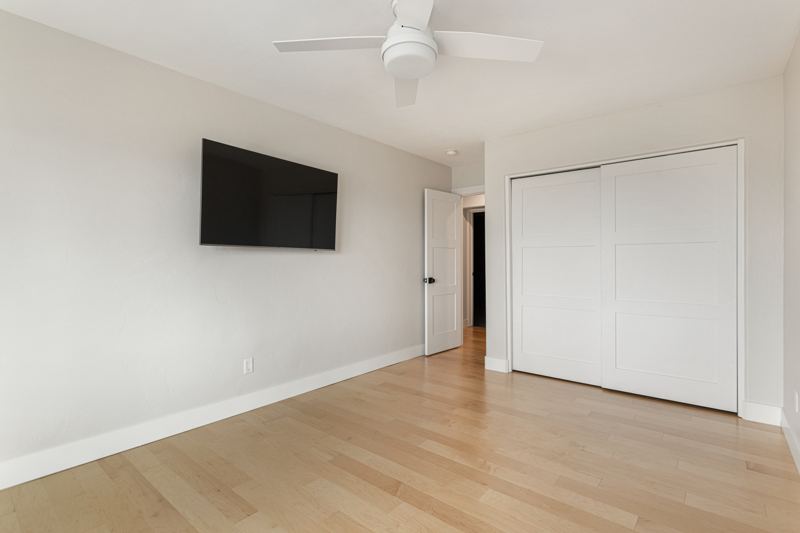 Bedroom with wall-mounted TV and closet
