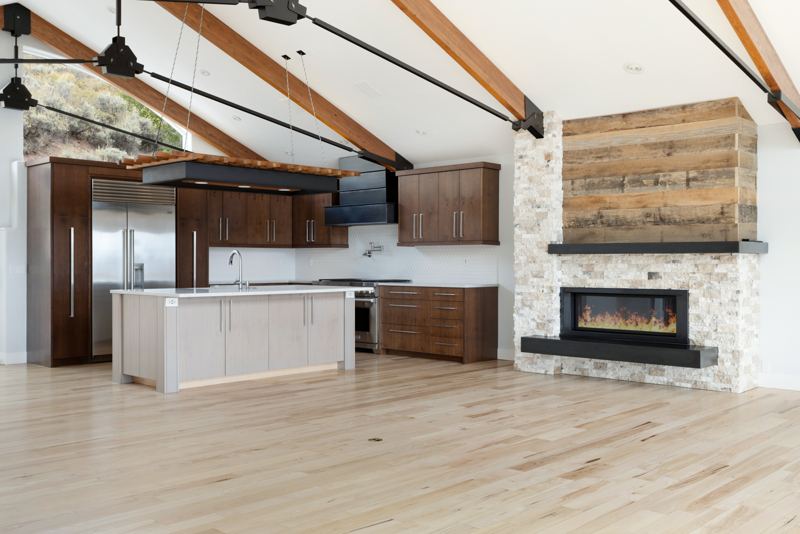 Kitchen, island, and fireplace under vaulted beams
